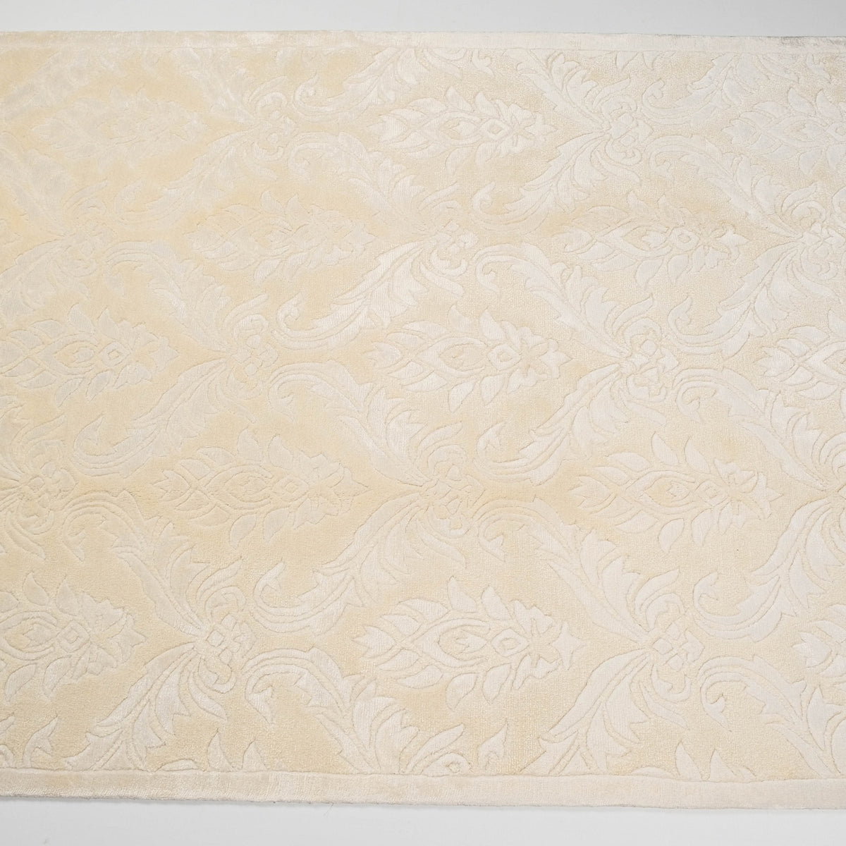 beyaz damask desenli halı — beyaz fonda cepheden geniş yüzey; damask motifleri baştan sona tekrar ediyor