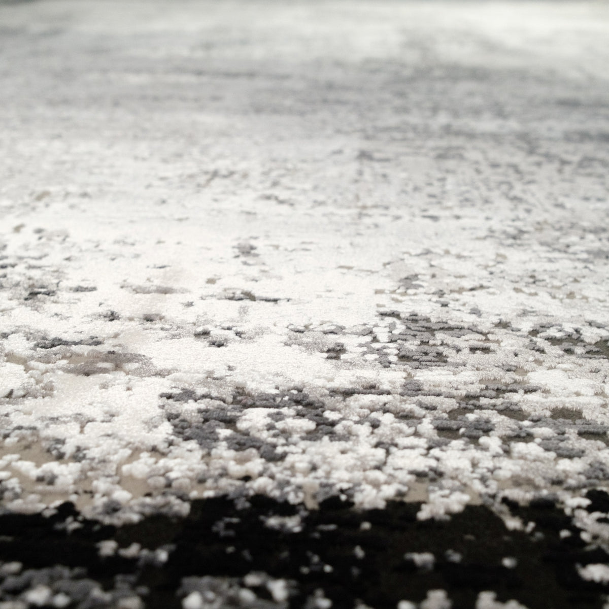 Fresco Series gray abstract acrylic rug — close-up of the transition; speckles scattering from the light field into the dark band
