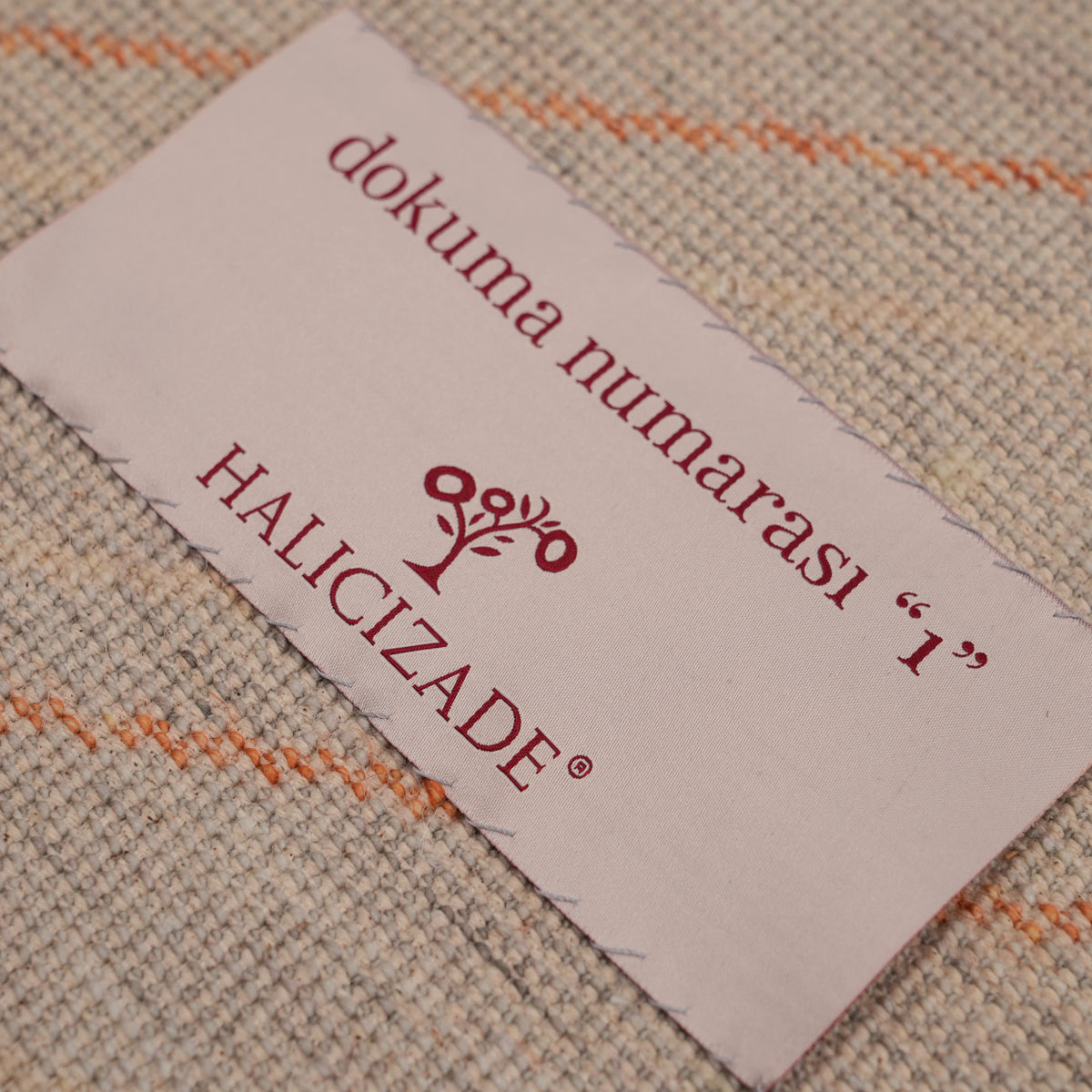 Günyolu Series orange-half-disc gray abstract rug — the cream woven label resting on the rug