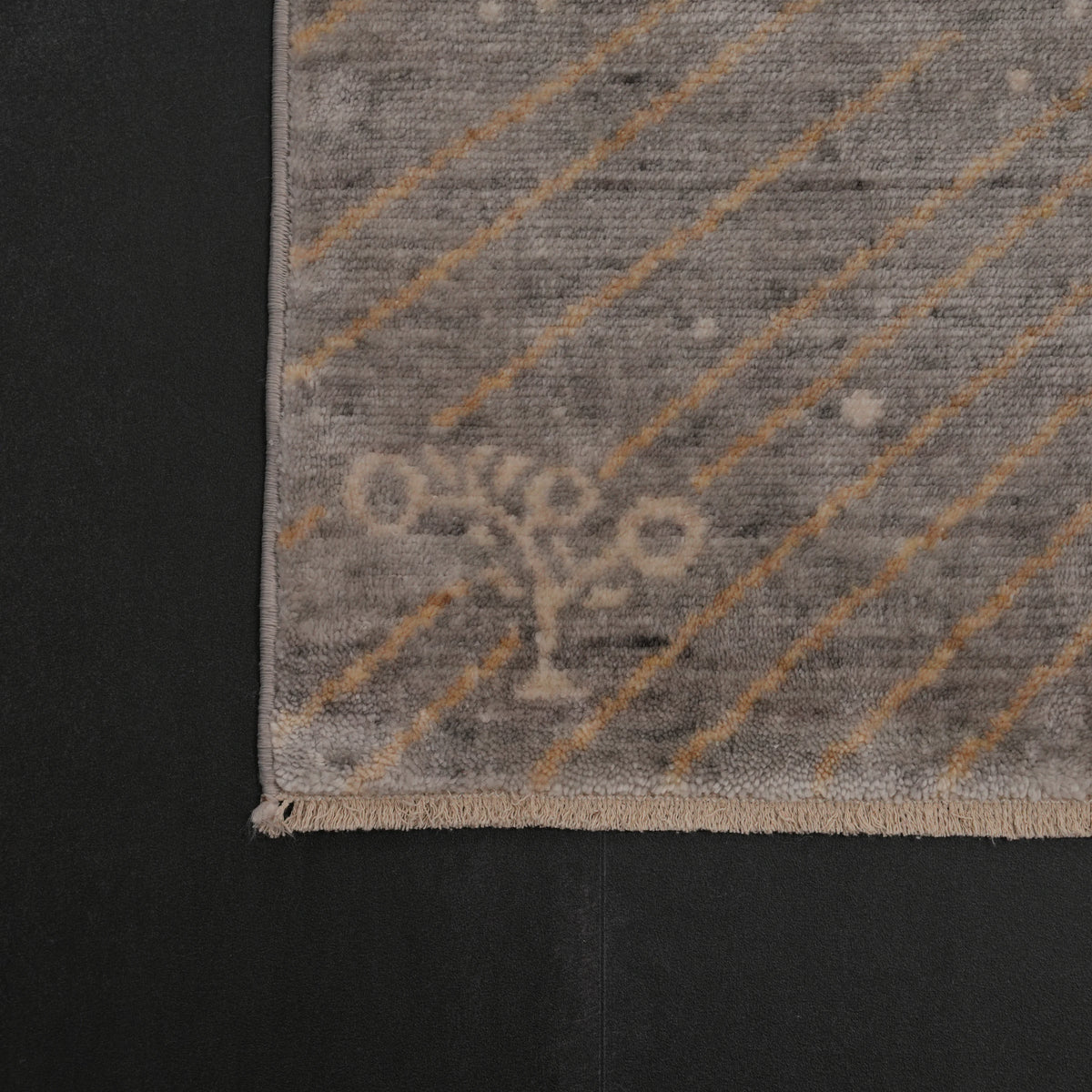 Günyolu Series amber-half-disc gray abstract rug — the corner on a dark ground, the woven maker's mark in the pile and the fringe