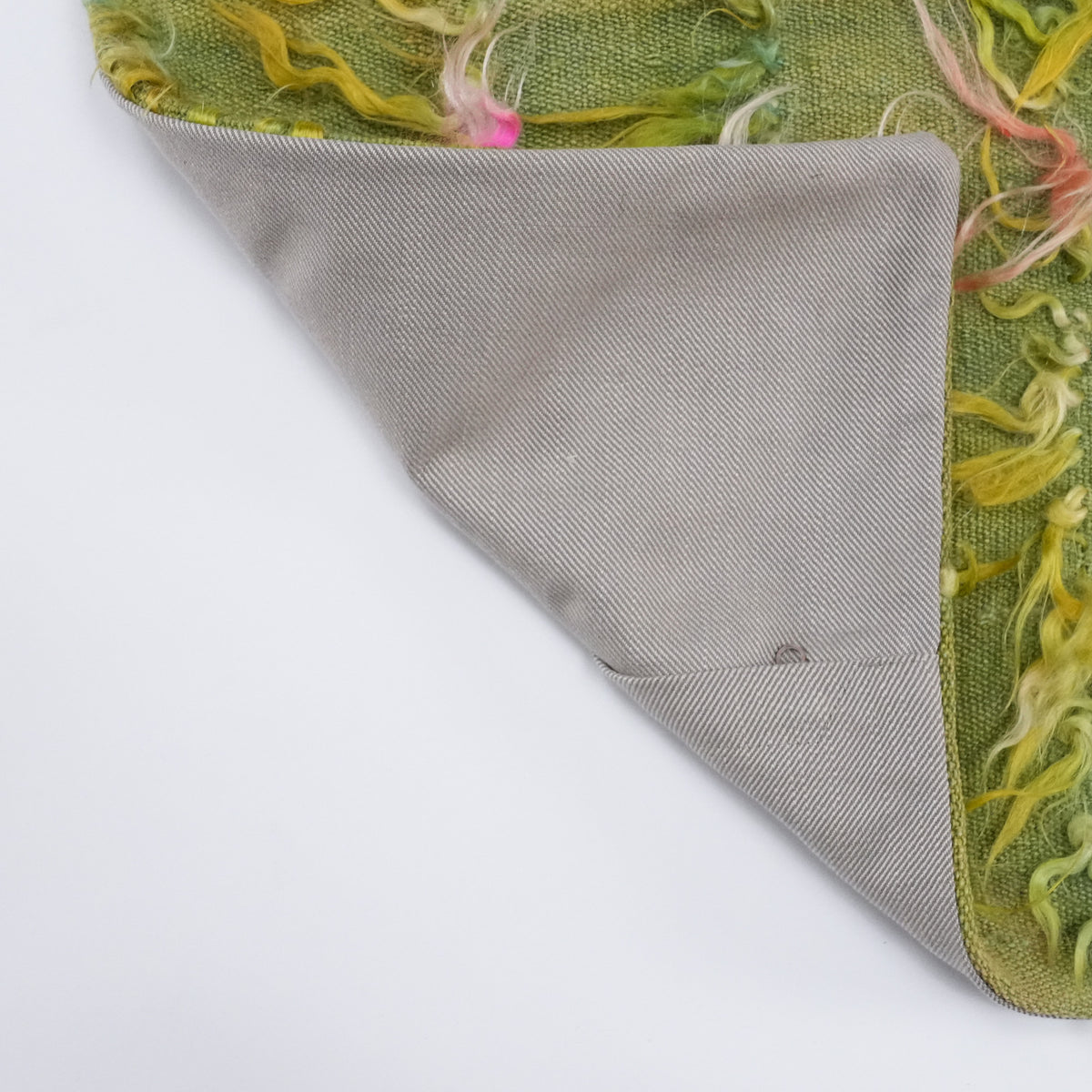 Green scattered-motif cushion covers — corner folded back on white, plain gray back face underneath