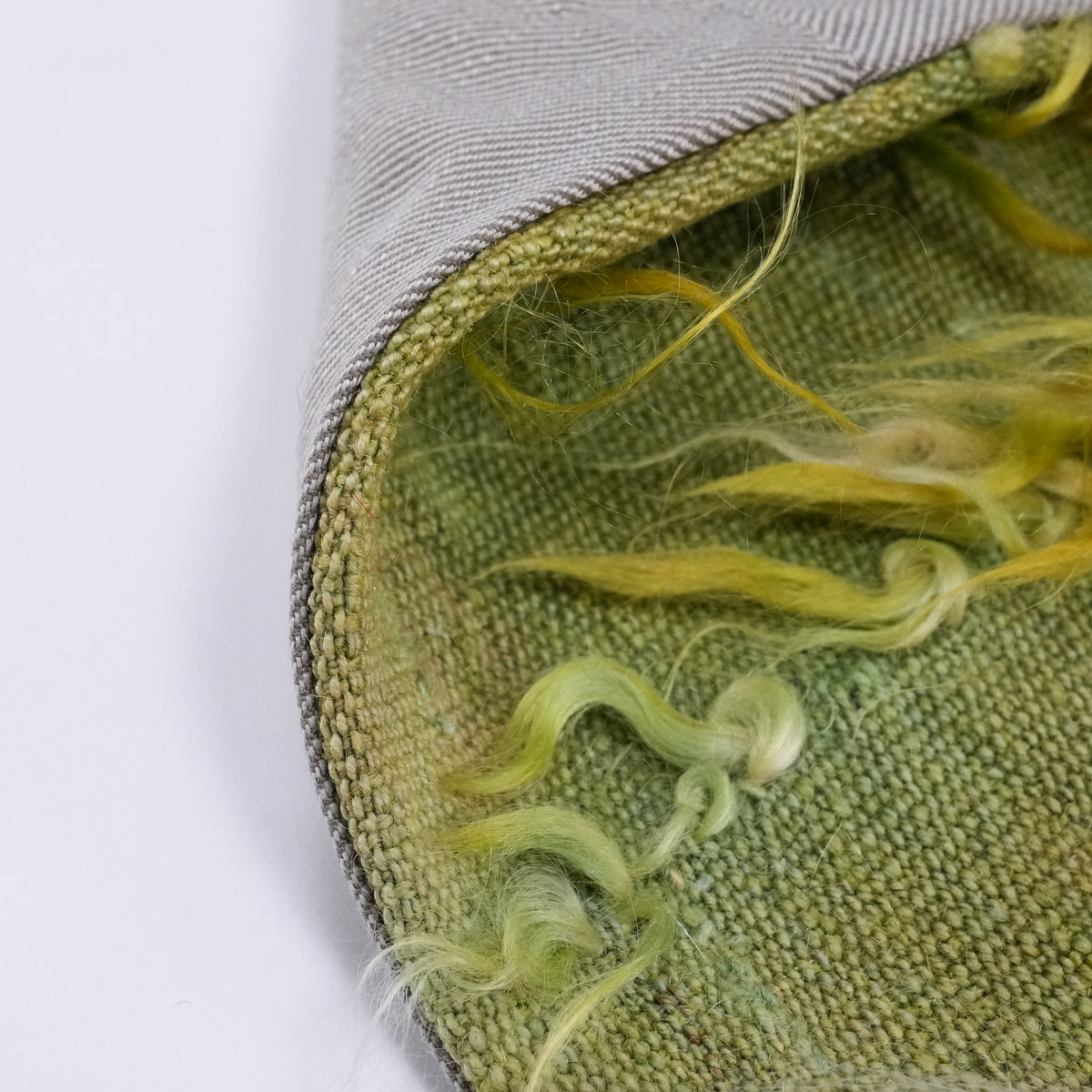 Green scattered-motif cushion covers — gray back face at the curling edge beside the yellow-green front