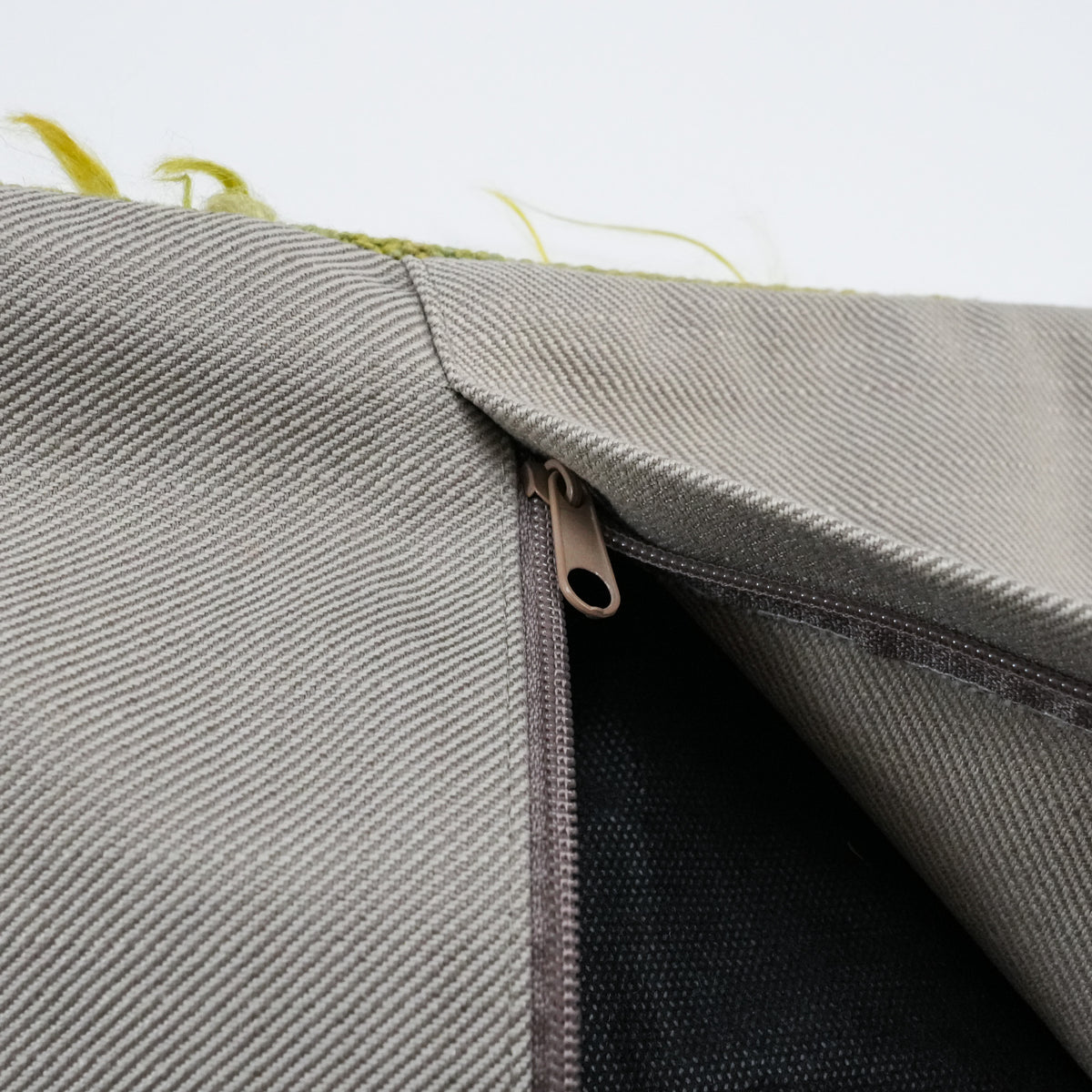 Green scattered-motif cushion covers — half-open zipper at the corner of the gray back and the dark lining