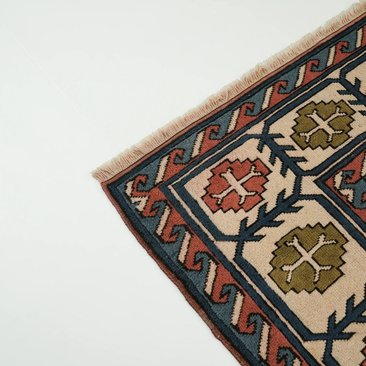 Multicolor Anatolian-pattern rug — close to a corner; the cream fringe and the star motifs in the border