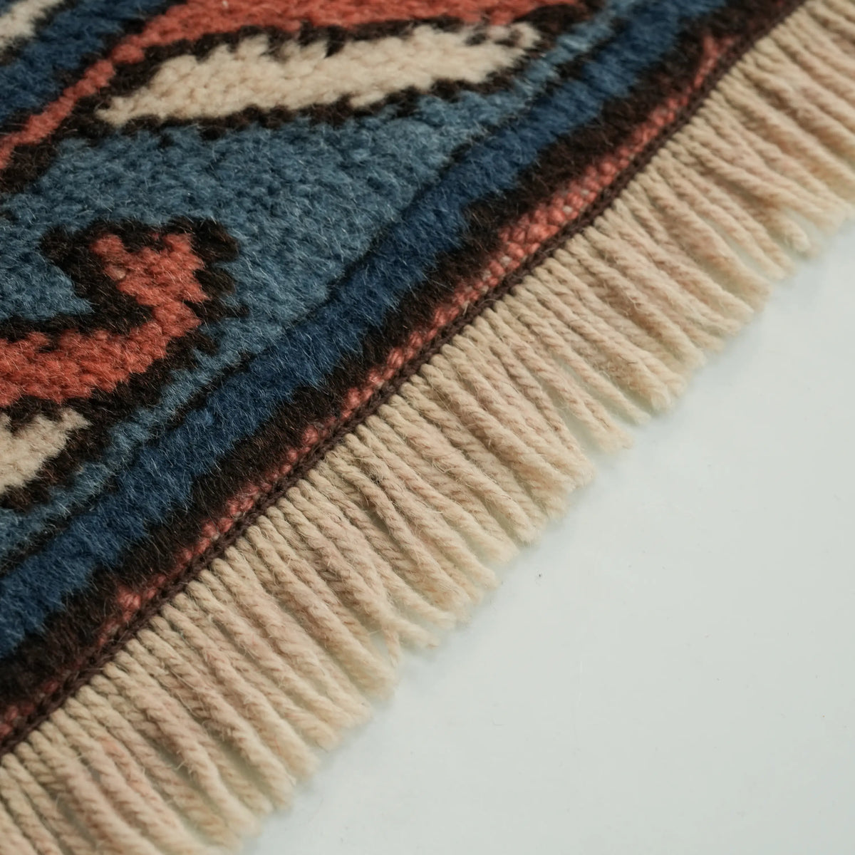 Multicolor Anatolian-pattern rug — close to the end at an angle; the row of fringe and the border at the edge