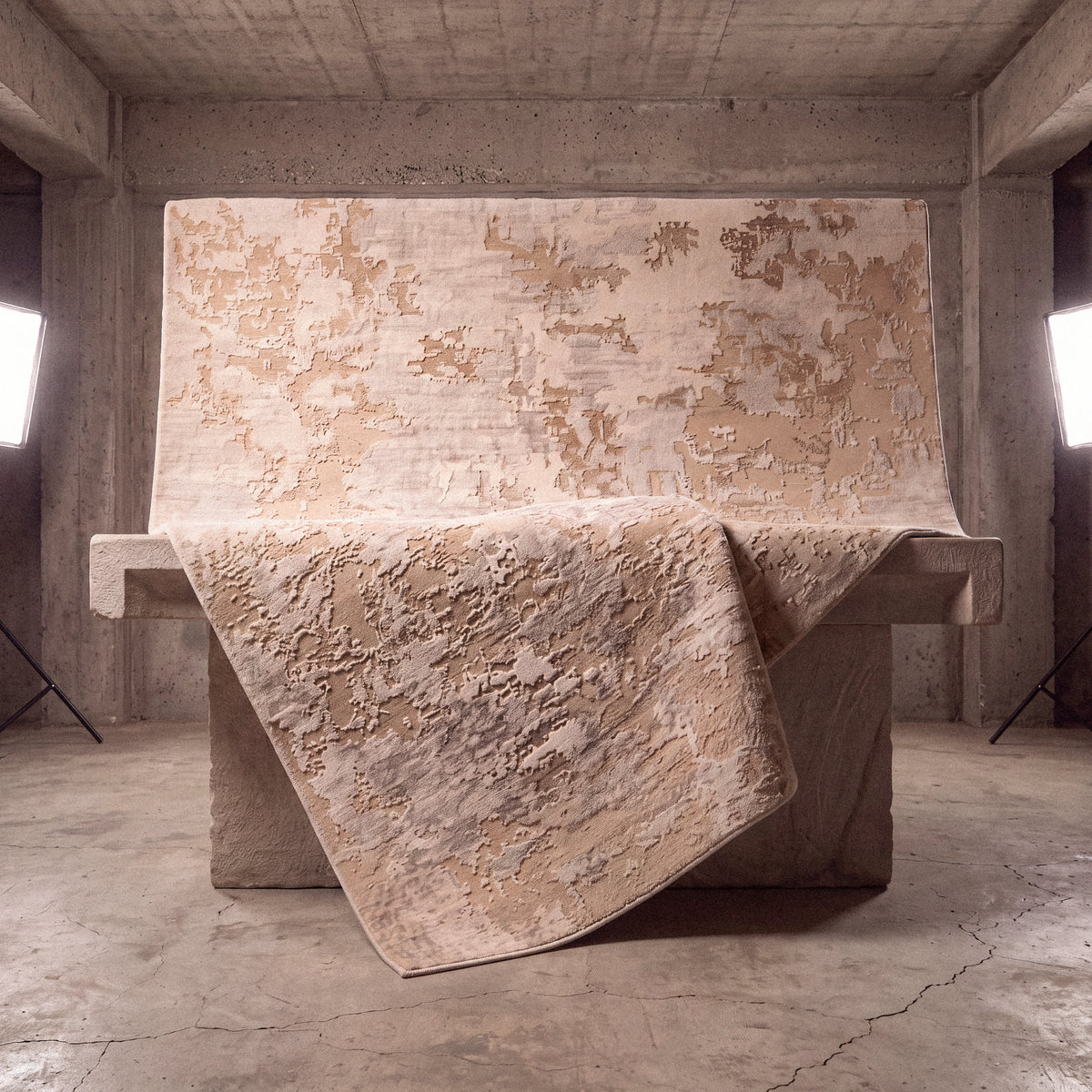 Maison Series cream abstract-pattern rug — spread on a stone plinth in a concrete space, edge hanging down