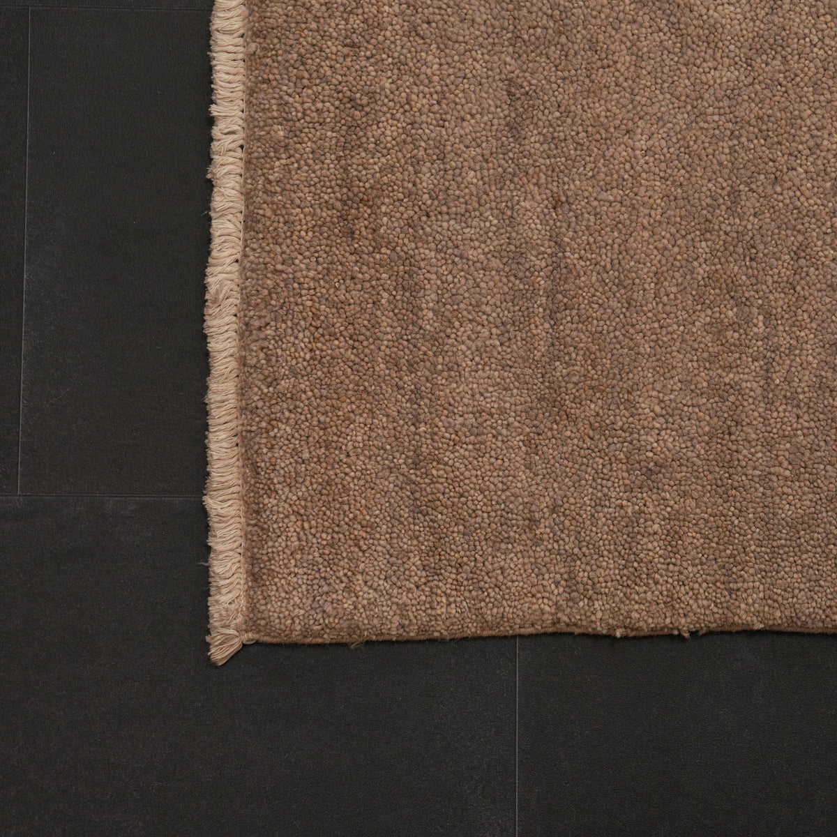 Retro Series plain gray rug — corner on a dark background, a thin cream fringe end