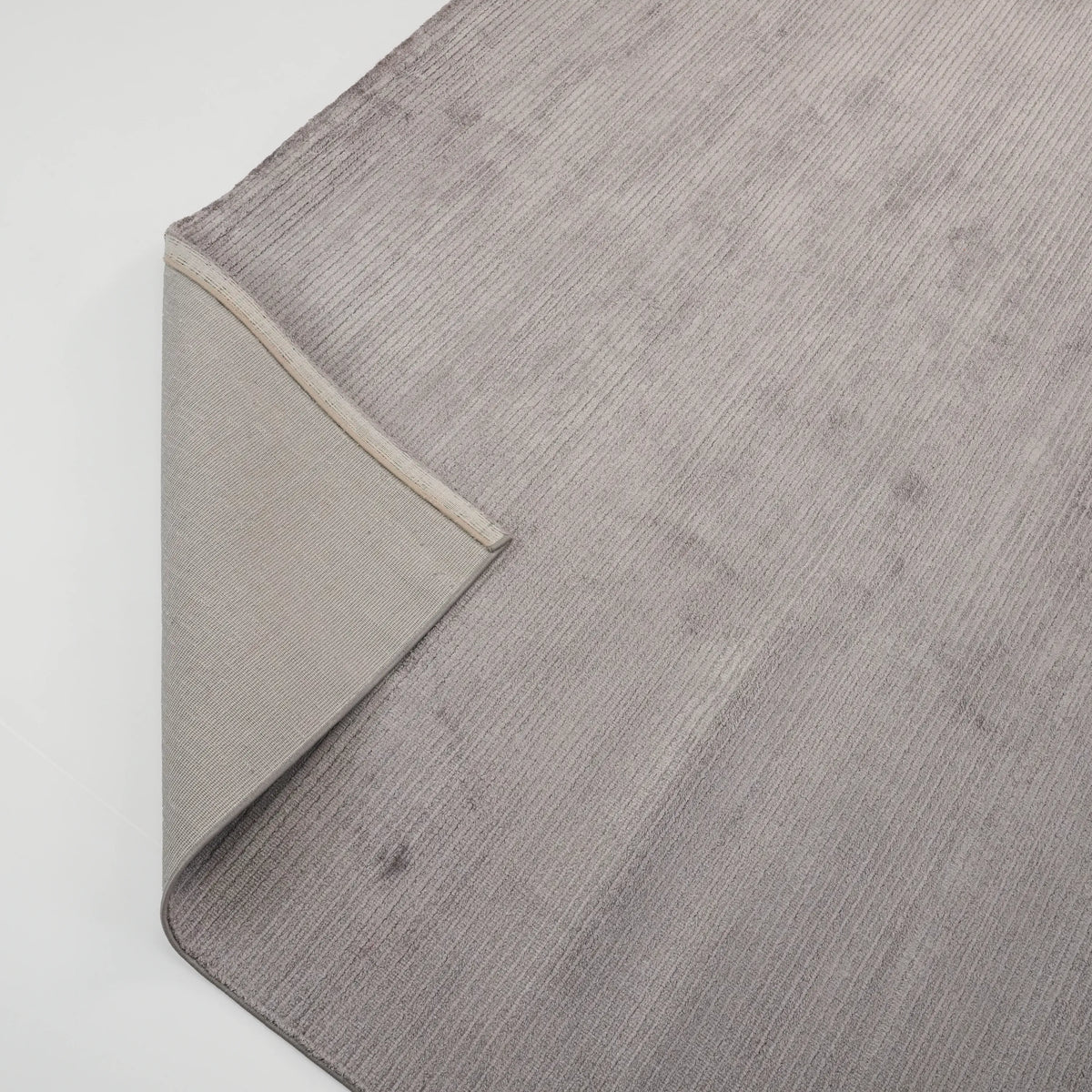 Soft Line Series striped rug — the corner folded back, the flat woven reverse beneath