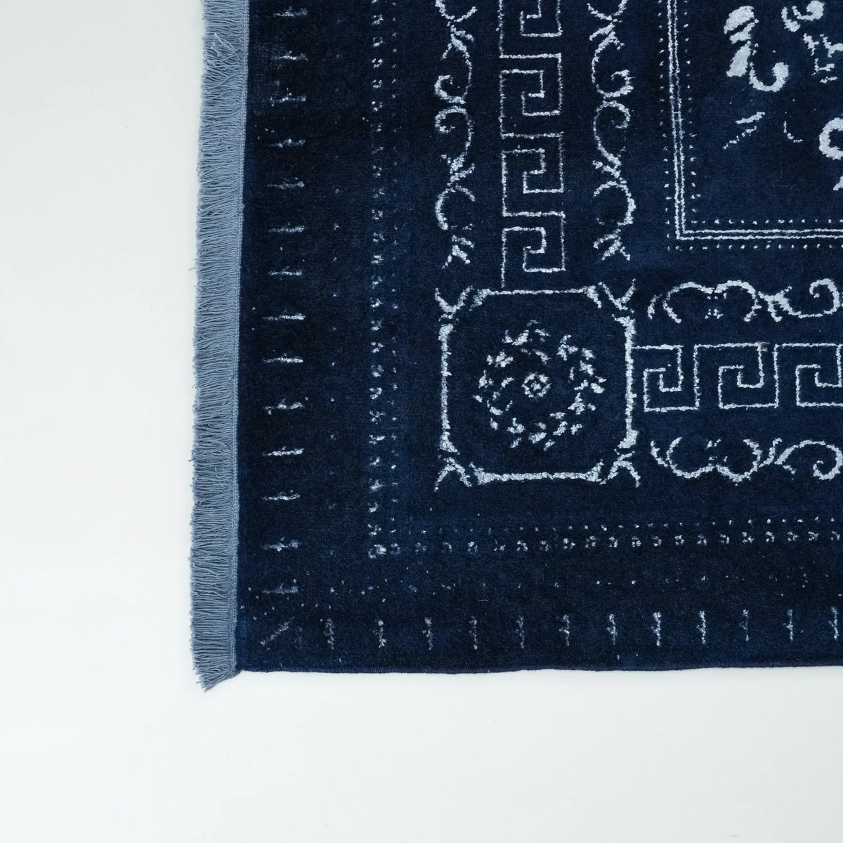 Versace Series navy medallion rug — corner close up; the meander border and the fringe at the left