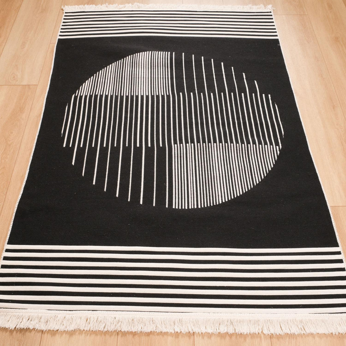 Kehribar Series black striped kilim — full length on parquet, a large circle on black, striped band and fringe below