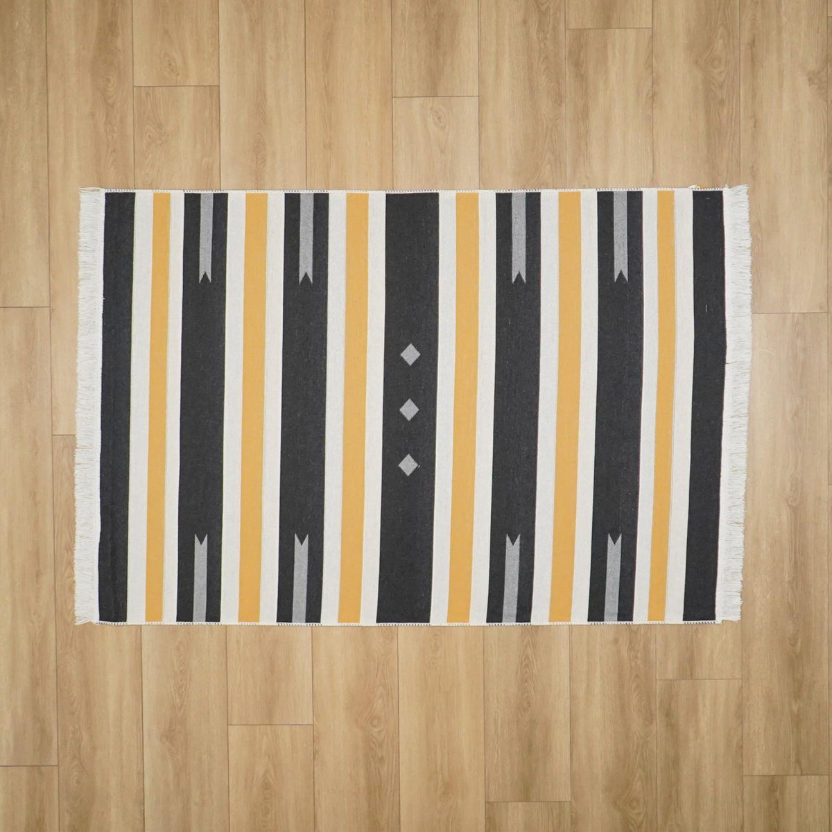 Kehribar Series gray striped kilim — from above on wide parquet boards, fringe at both short ends