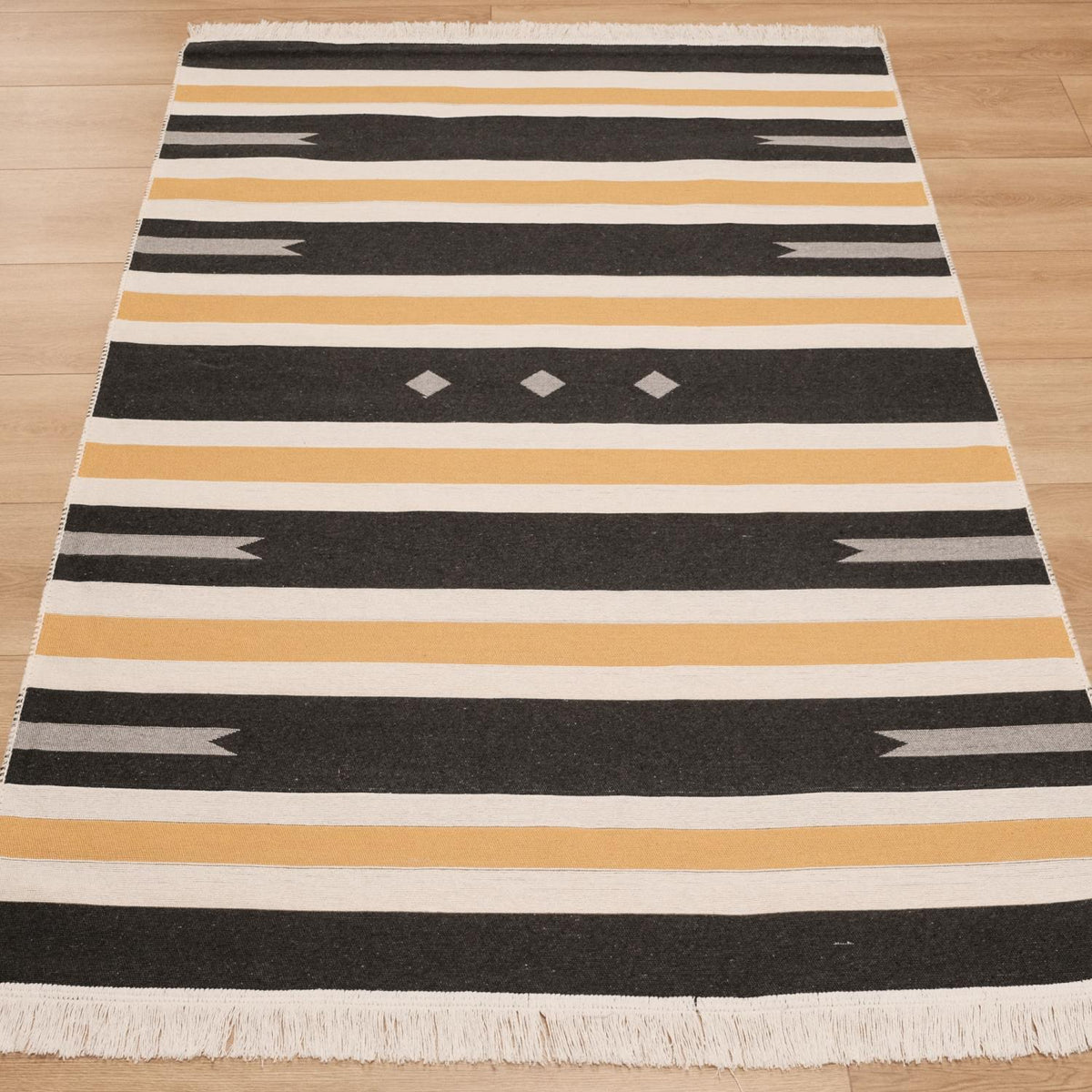Kehribar Series gray striped kilim — lengthwise on parquet, mustard and dark bands, three small diamonds centered