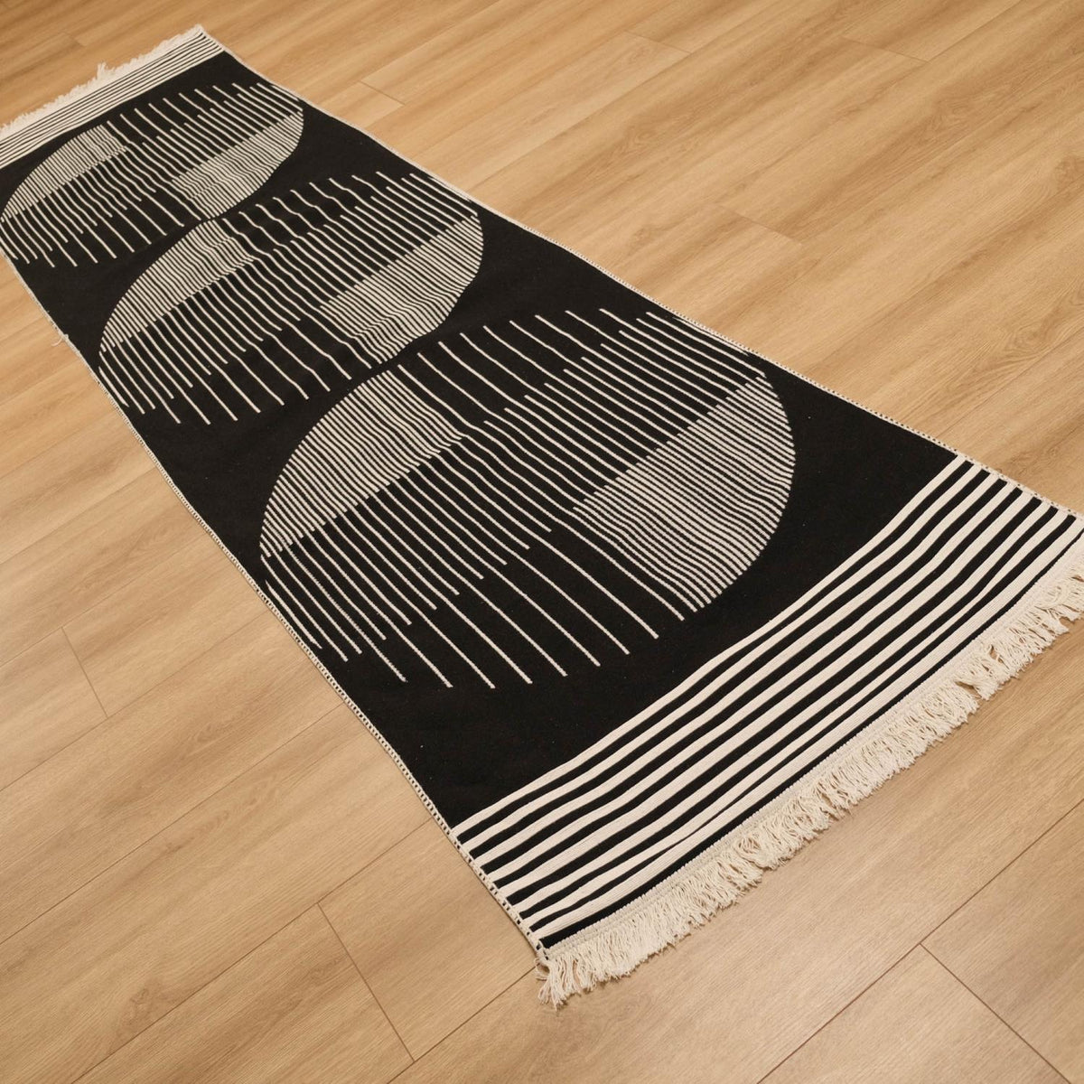 Kehribar Series black striped kilim — runner in diagonal perspective, three rows of circles, fringe at lower right