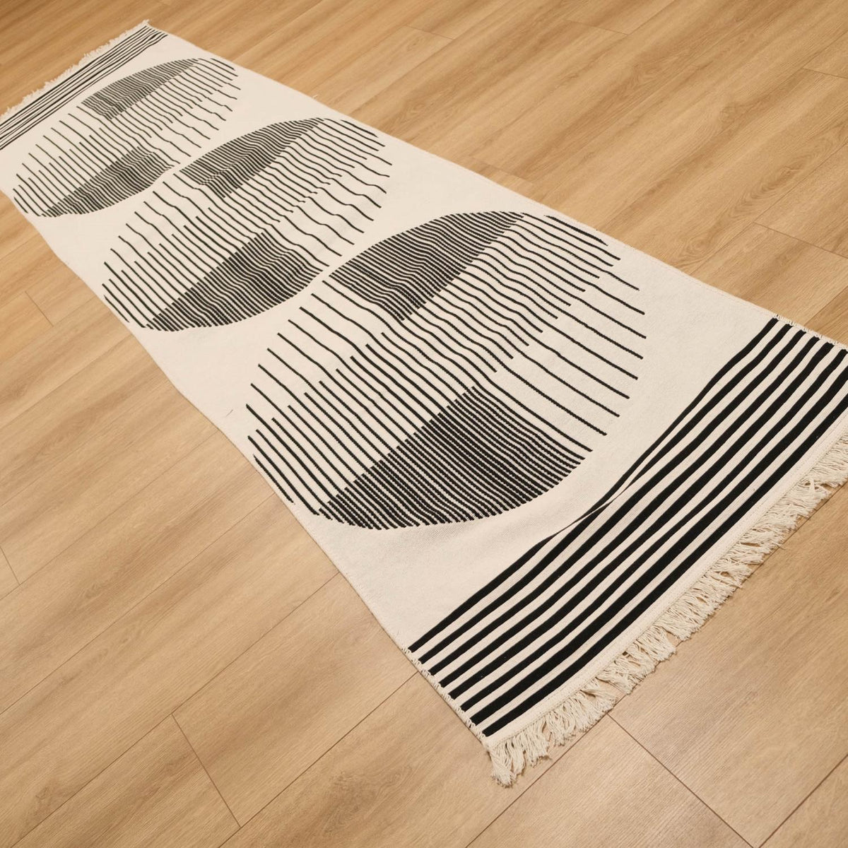 Kehribar Series black striped kilim — runner crossing the frame; circles beside the striped band