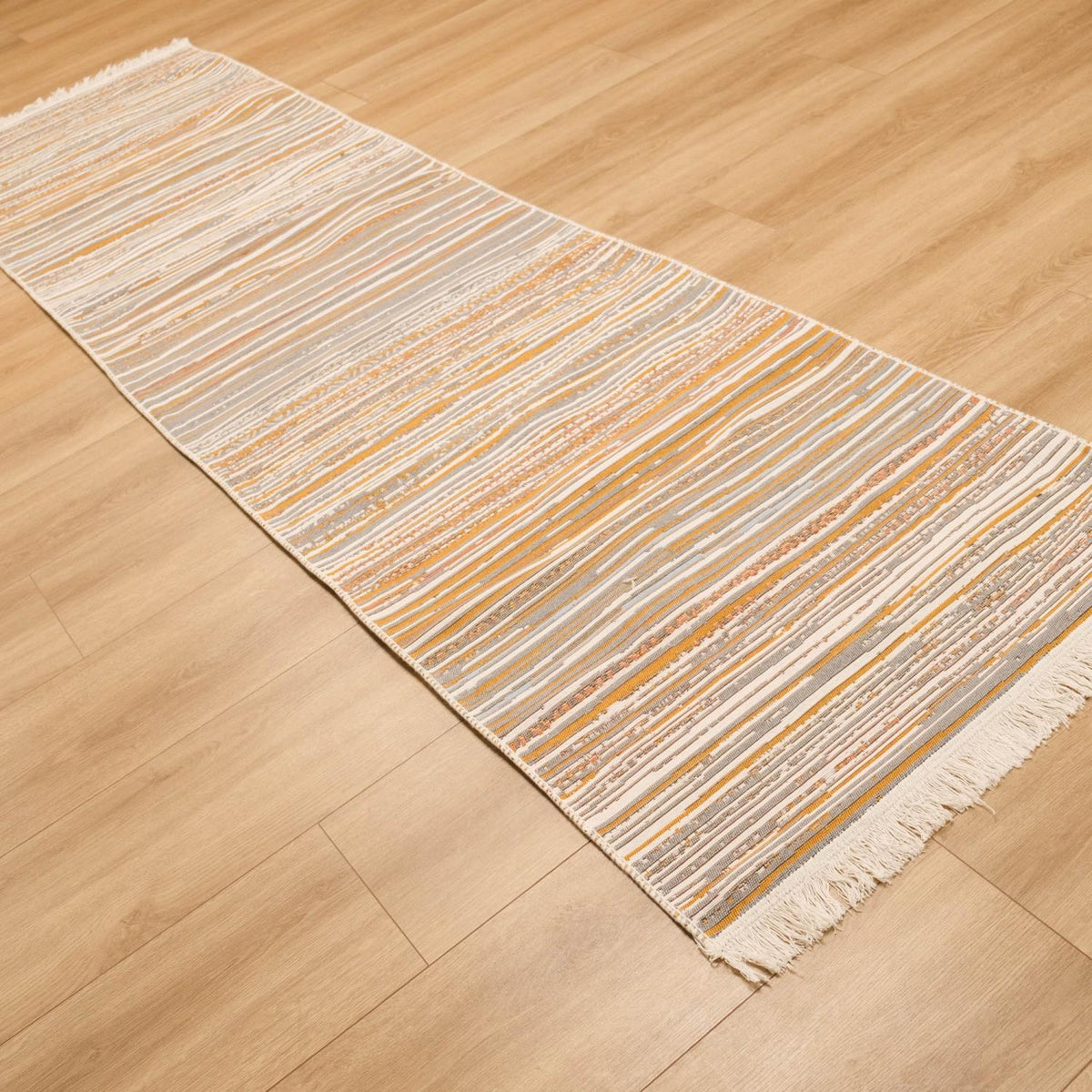 Kehribar Series multicolor striped kilim — set diagonally on parquet, warm cream and orange bands dominant