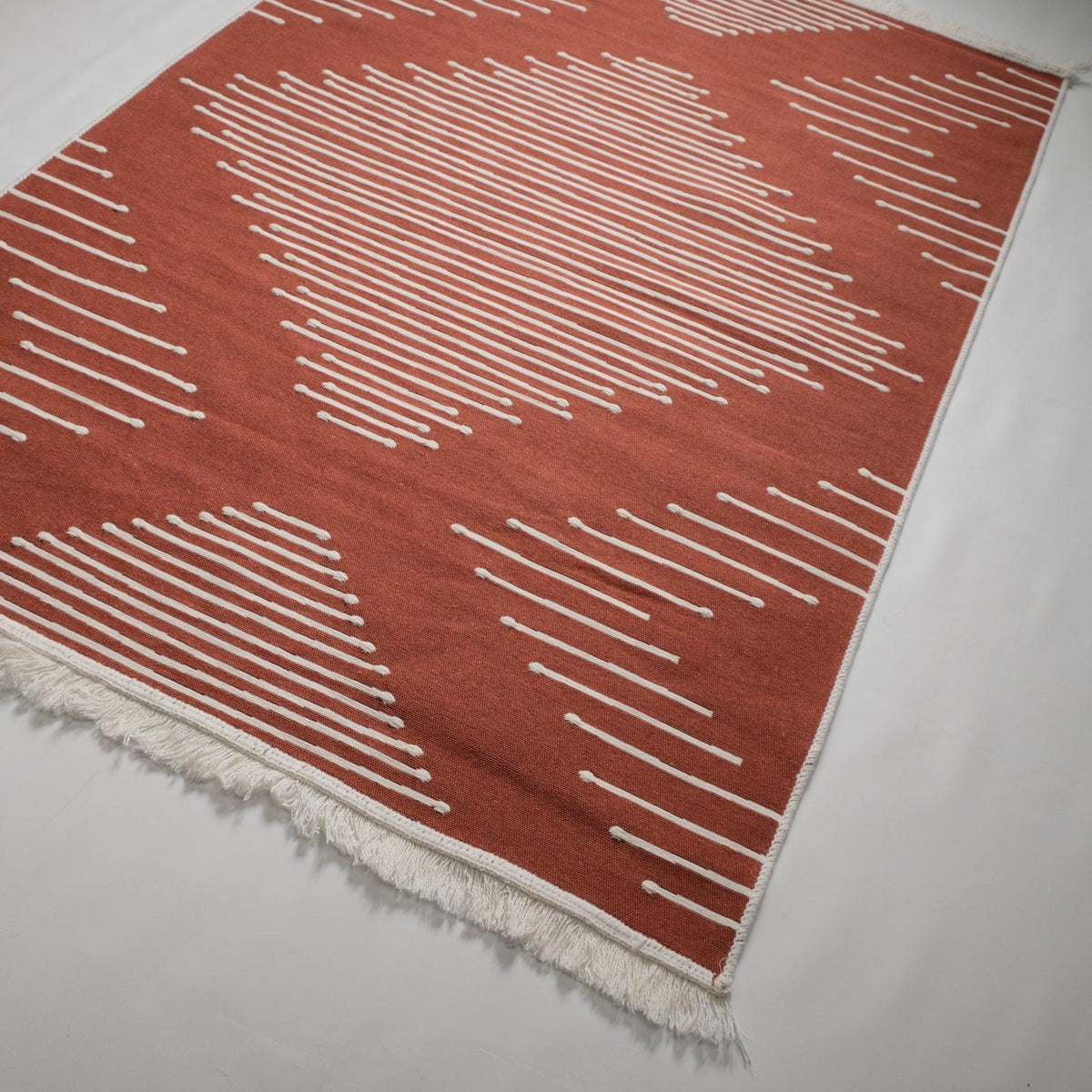 Kehribar serisi geometrik terra kilim — duvar dibinde açılı duruş, krem çizgiler terra zeminde