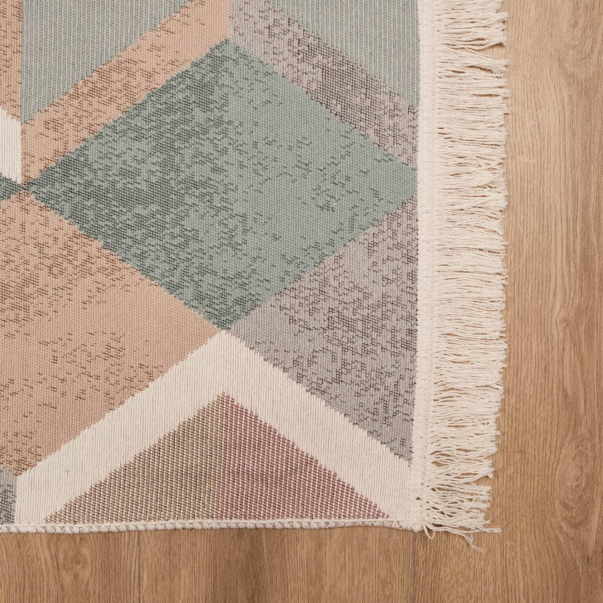 Kehribar Series multicolor triangle-pattern kilim — corner on parquet, a thin row of fringe along the side edge