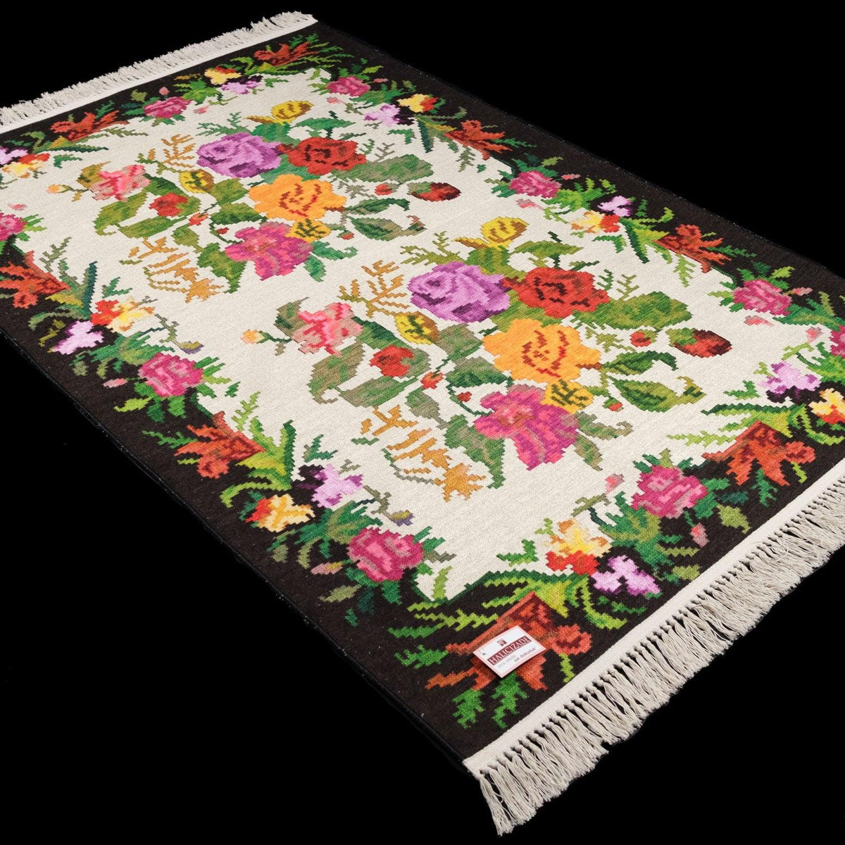 Kehribar Series cream Karabagh-pattern rug — angled full view on black; colored floral area inside a dark frame