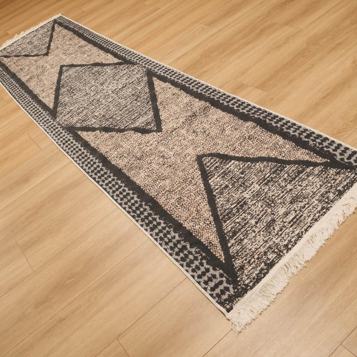 Kehribar gri geometrik desenli kilim — ahşap zeminde çapraz duruş, bej ağırlıklı zemin tonu